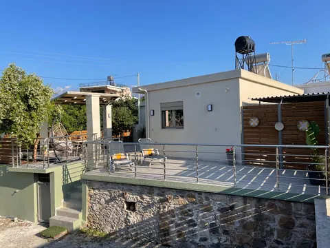The house and its raised deck seen from below, stone wall beneath
