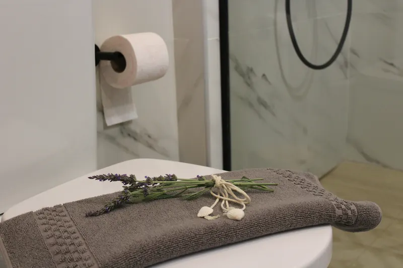 A sprig of lavender tied with string on a folded grey towel in the bathroom