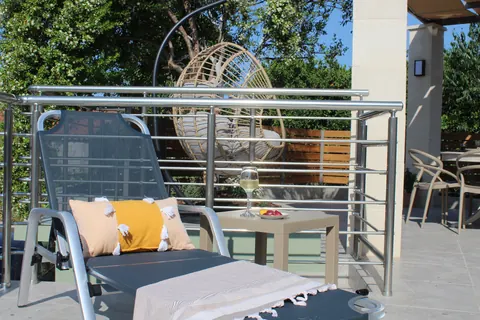 A sun lounger on the deck with the hanging chair behind