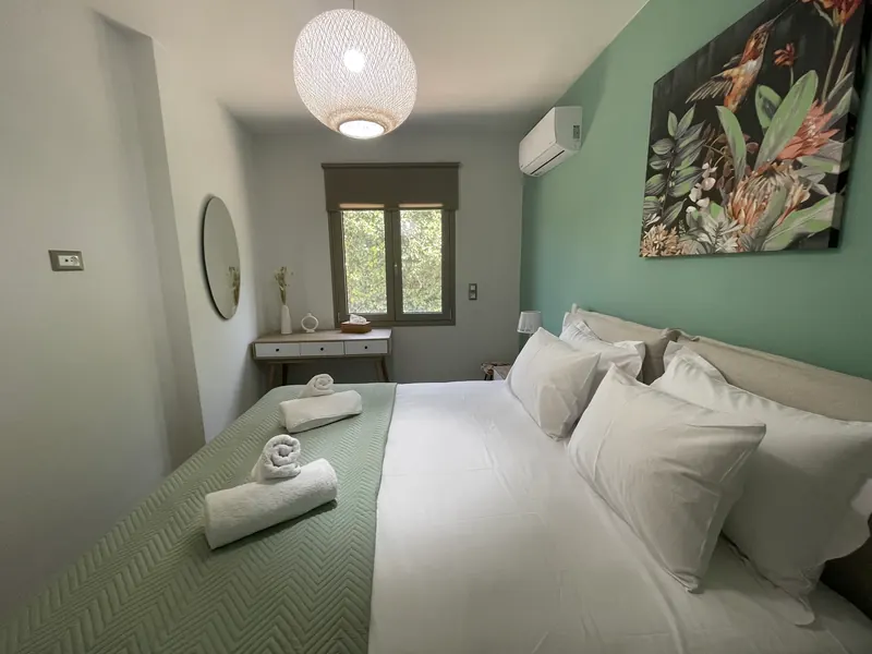 The Mint Room: a large bed with white linen and a green throw, a mint-green wall with a hummingbird painting