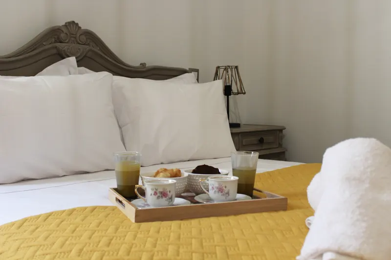 A breakfast tray with coffee, juice and pastries on the yellow quilt of the Mustard Room bed