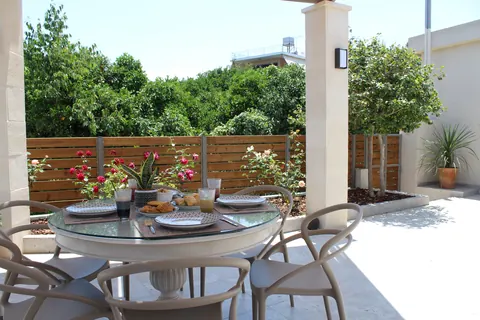 Breakfast table under the pergola with red roses behind