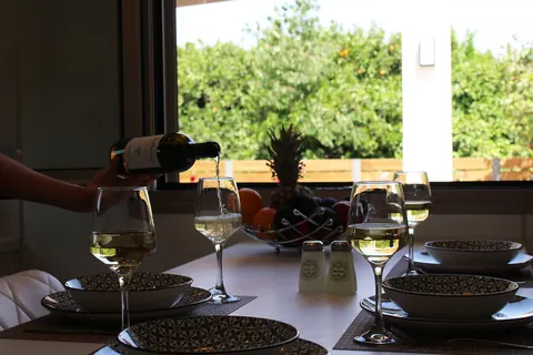 White wine being poured at the table, orange trees through the window